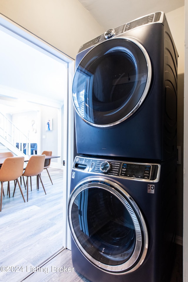 clothes washing area with stacked washing maching and dryer and light wood-type flooring