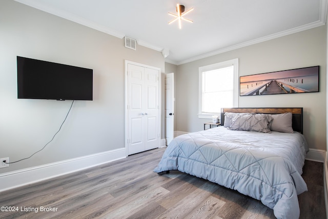 bedroom featuring baseboards, visible vents, wood finished floors, and ornamental molding