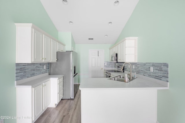 kitchen with vaulted ceiling, kitchen peninsula, stainless steel appliances, and sink