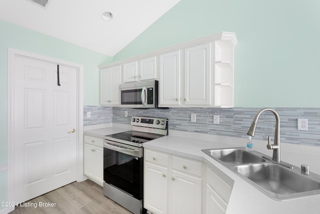 kitchen with appliances with stainless steel finishes, sink, decorative backsplash, lofted ceiling, and white cabinets