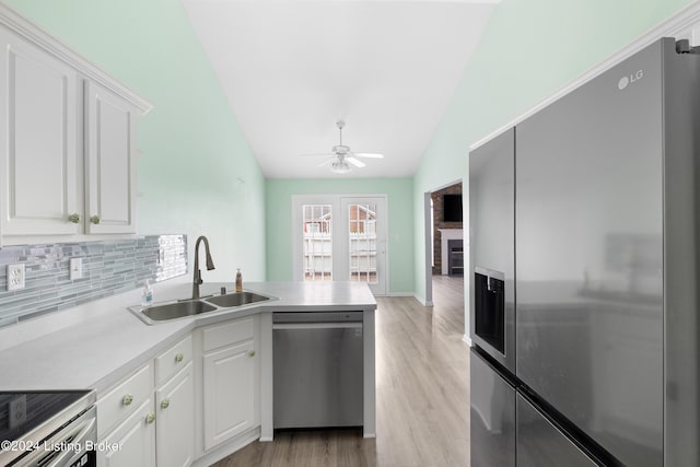 kitchen with vaulted ceiling, appliances with stainless steel finishes, sink, ceiling fan, and white cabinets