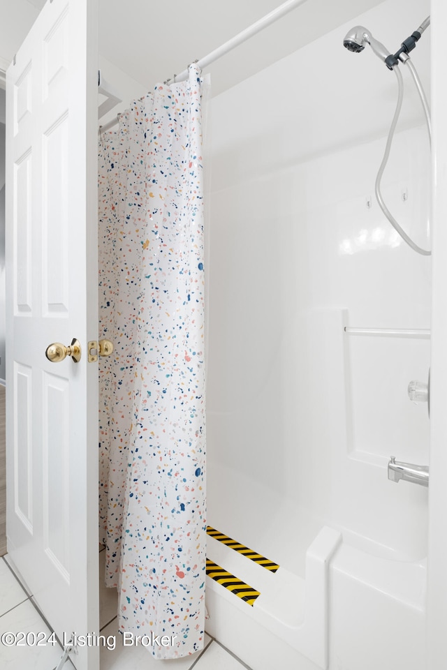 bathroom with curtained shower and tile patterned floors