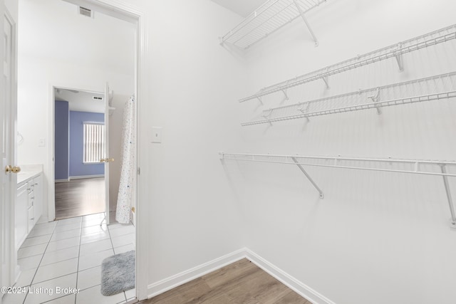 walk in closet with light hardwood / wood-style flooring