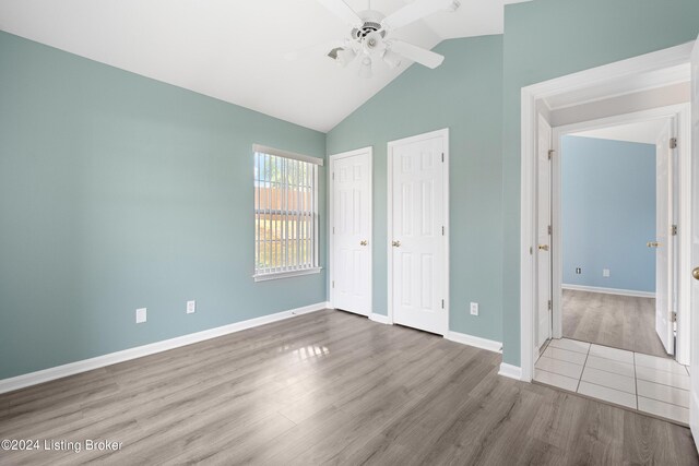 unfurnished bedroom with lofted ceiling, wood-type flooring, multiple closets, and ceiling fan