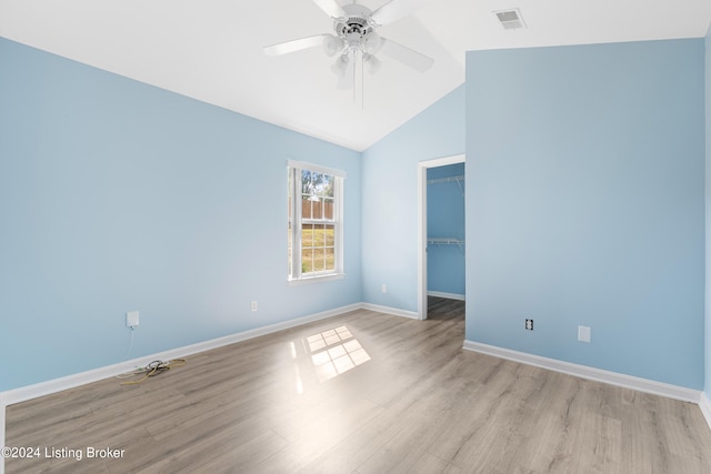 unfurnished bedroom featuring light hardwood / wood-style floors, ceiling fan, a spacious closet, and vaulted ceiling