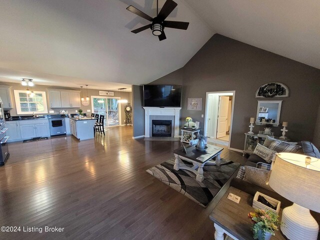 living room with ceiling fan, a tile fireplace, dark wood-type flooring, and a healthy amount of sunlight