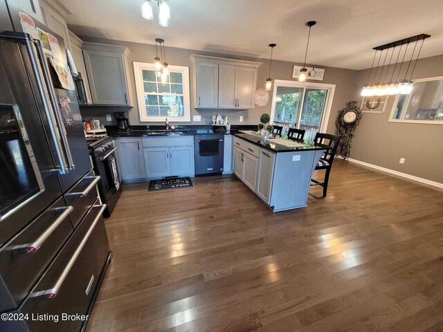 kitchen with stainless steel appliances, hanging light fixtures, a kitchen bar, and dark hardwood / wood-style floors