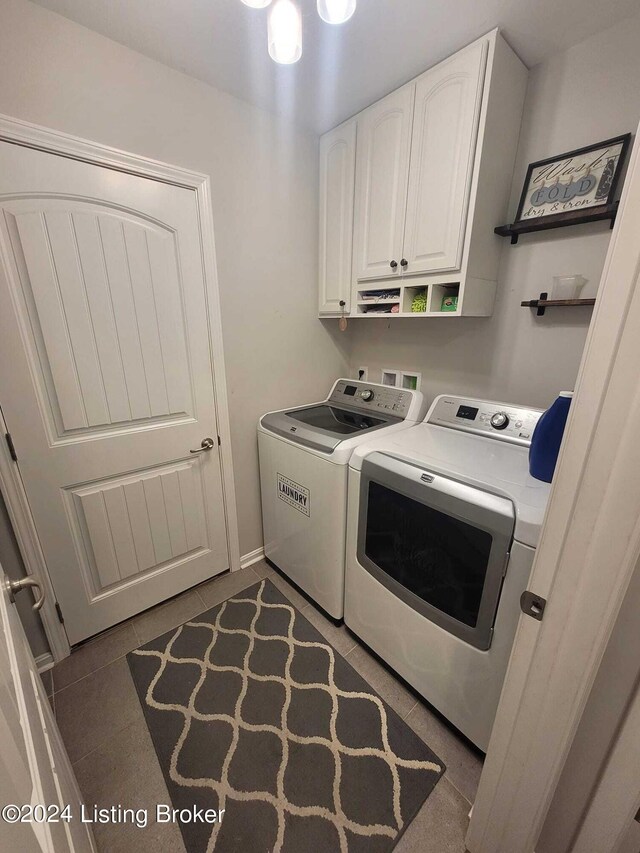 laundry area with washer and dryer, dark tile patterned floors, and cabinets