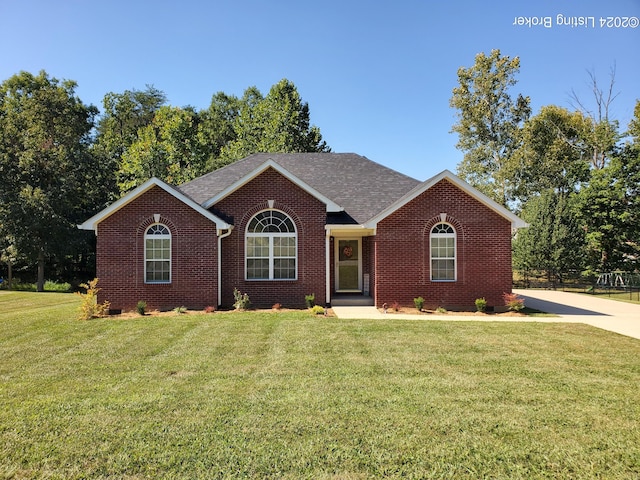 ranch-style house with a shingled roof, a front yard, and brick siding