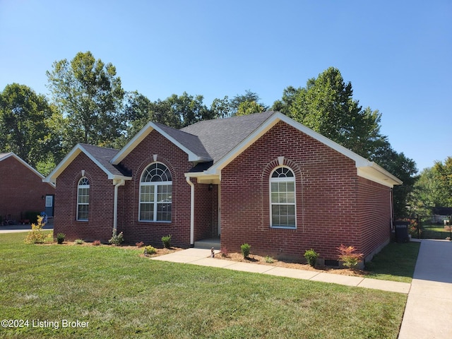 view of front of home featuring roof with shingles, a front lawn, and brick siding