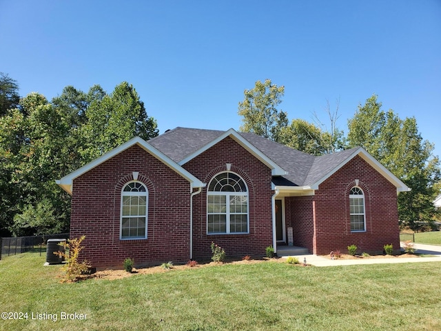 ranch-style home with brick siding, roof with shingles, a front yard, and fence