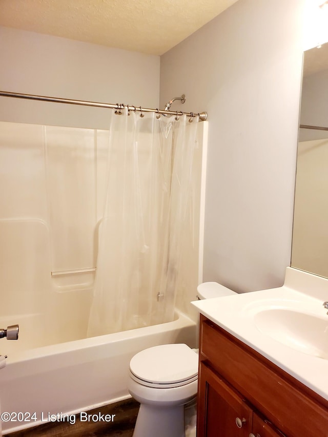 bathroom featuring shower / tub combo with curtain, vanity, toilet, and a textured ceiling