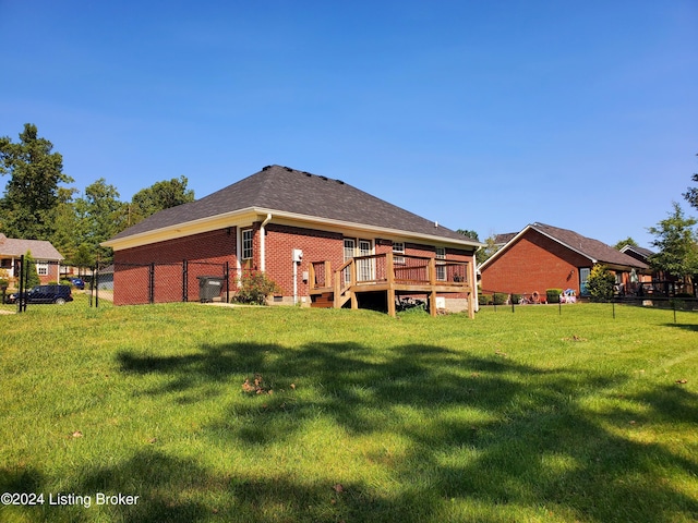 rear view of property with brick siding, a yard, a deck, and fence