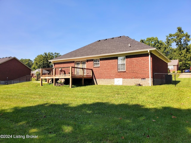 rear view of house with brick siding, a lawn, a wooden deck, and fence