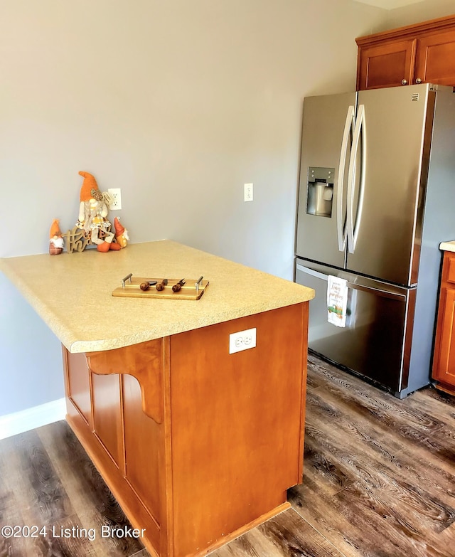 kitchen with brown cabinets, dark wood-type flooring, a peninsula, light countertops, and stainless steel refrigerator with ice dispenser