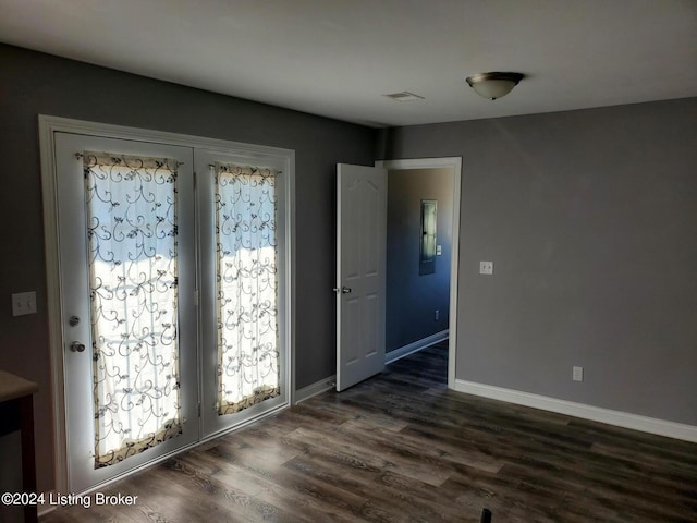 empty room with baseboards and dark wood-type flooring