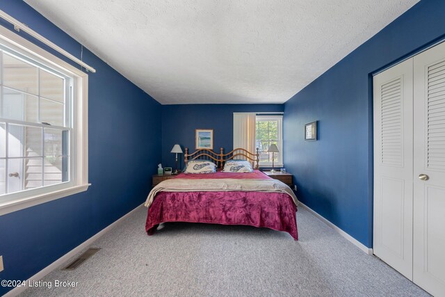 carpeted bedroom featuring a textured ceiling and a closet