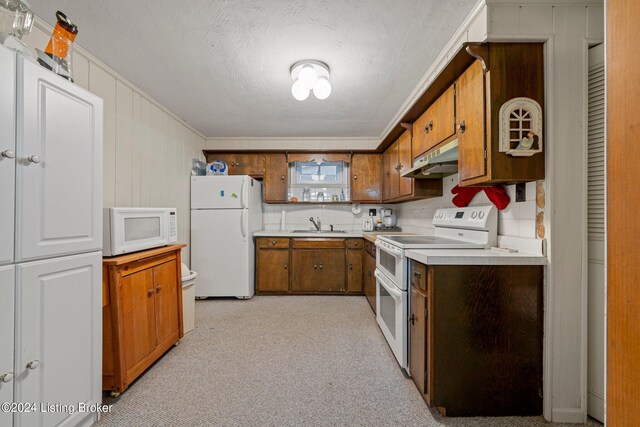 kitchen featuring light carpet, white appliances, a textured ceiling, wood walls, and sink