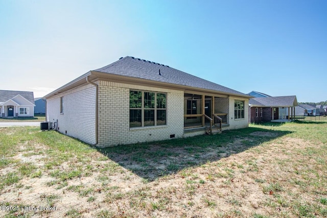 back of property with central AC and a lawn