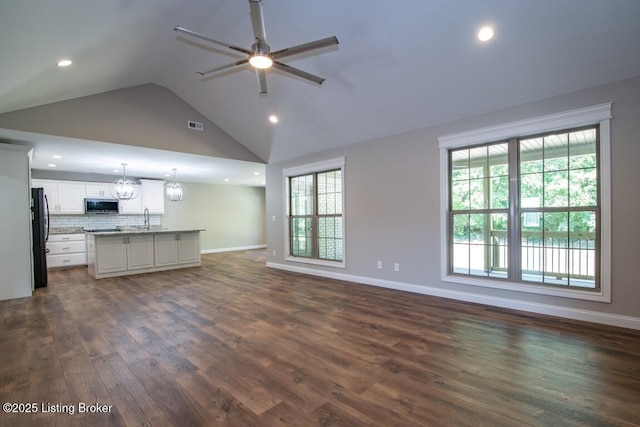 unfurnished living room with vaulted ceiling, sink, ceiling fan with notable chandelier, and dark hardwood / wood-style floors