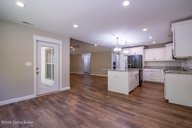 kitchen featuring white cabinetry, tasteful backsplash, an island with sink, dark hardwood / wood-style flooring, and decorative light fixtures