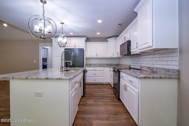 kitchen with tasteful backsplash, black appliances, an island with sink, pendant lighting, and white cabinets