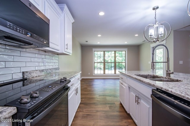 kitchen with stainless steel appliances, sink, white cabinets, and light stone counters