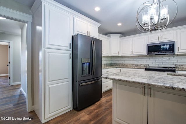 kitchen featuring black fridge, backsplash, white cabinets, and light stone counters