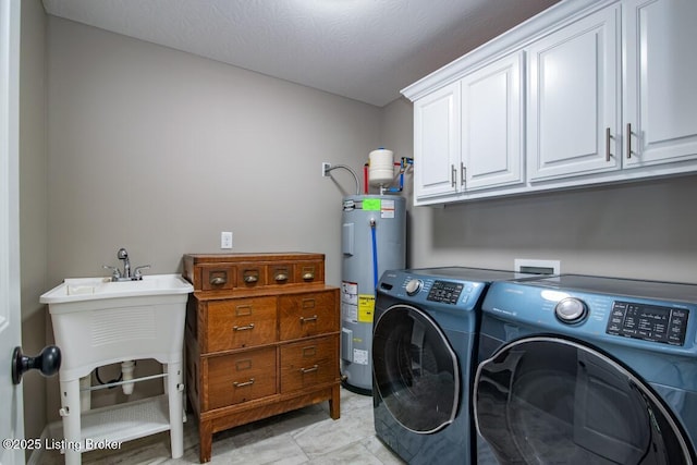 clothes washing area featuring cabinets, washing machine and clothes dryer, and water heater