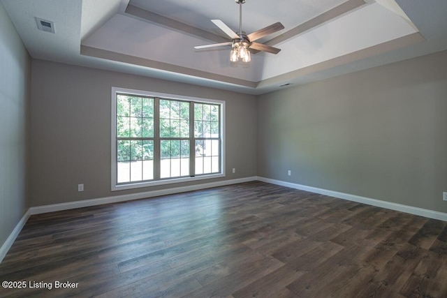 spare room featuring ceiling fan, dark hardwood / wood-style floors, and a raised ceiling