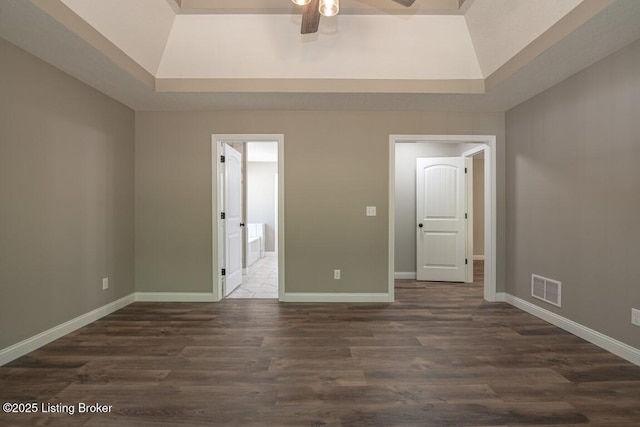 spare room featuring dark hardwood / wood-style flooring, a raised ceiling, and ceiling fan