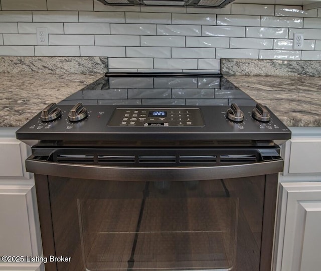 room details featuring backsplash, electric range, and light stone countertops