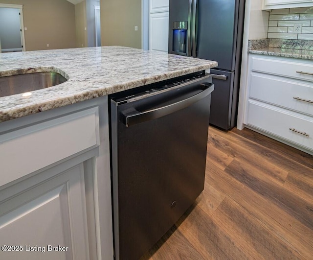 kitchen featuring dark wood-type flooring, light stone counters, dishwasher, refrigerator with ice dispenser, and white cabinets