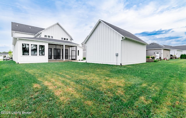 back of house featuring a sunroom and a lawn