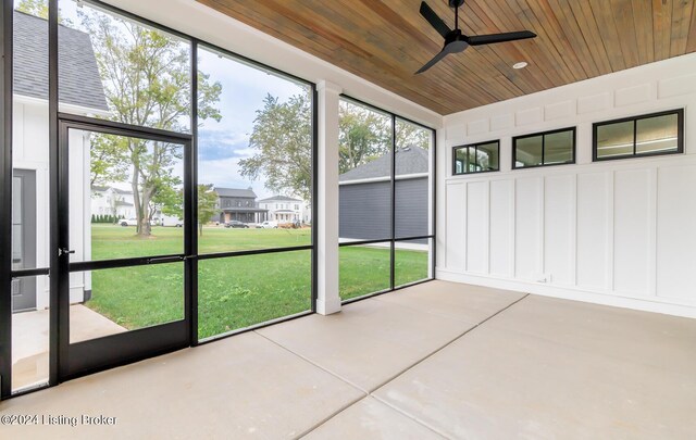 unfurnished sunroom with ceiling fan, a wealth of natural light, and wood ceiling