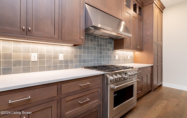 kitchen with high end stainless steel range oven, ventilation hood, dark wood-type flooring, and backsplash