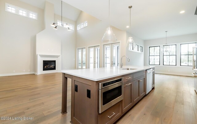 kitchen featuring appliances with stainless steel finishes, sink, pendant lighting, and a kitchen island with sink