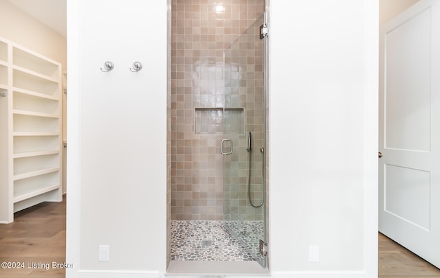 bathroom with hardwood / wood-style flooring and a shower with shower door