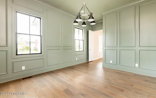 unfurnished dining area with a notable chandelier and light hardwood / wood-style floors