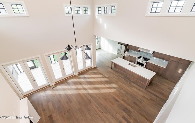 interior space with a towering ceiling, a wealth of natural light, french doors, and hardwood / wood-style flooring