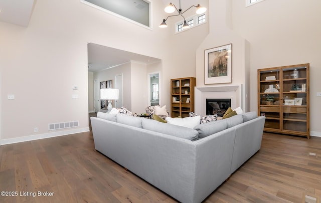 living room with hardwood / wood-style floors, a notable chandelier, and a high ceiling