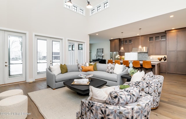 living room featuring french doors, a high ceiling, and light wood-type flooring