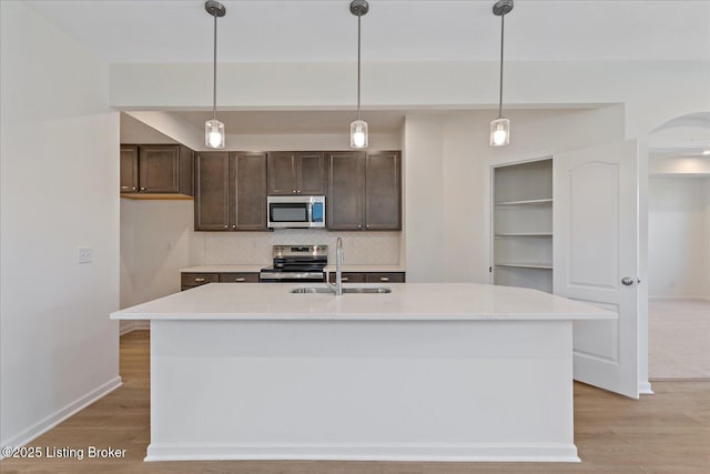 kitchen featuring stainless steel appliances, a sink, light countertops, and light wood-style floors