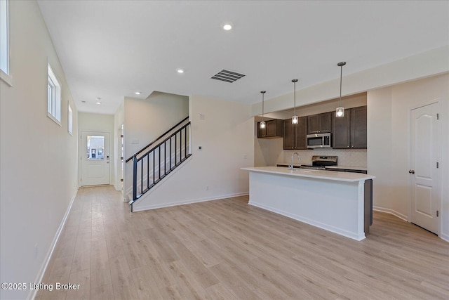 kitchen featuring dark brown cabinetry, visible vents, stainless steel appliances, light countertops, and light wood-type flooring