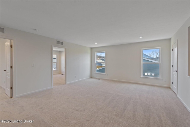 empty room with baseboards, visible vents, and light colored carpet