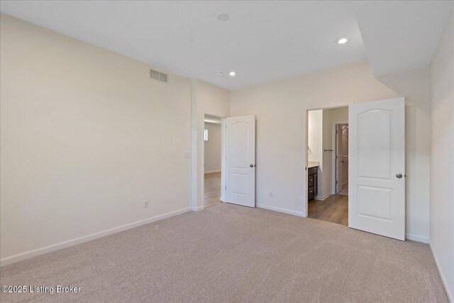 unfurnished bedroom with visible vents, baseboards, ensuite bathroom, carpet, and recessed lighting