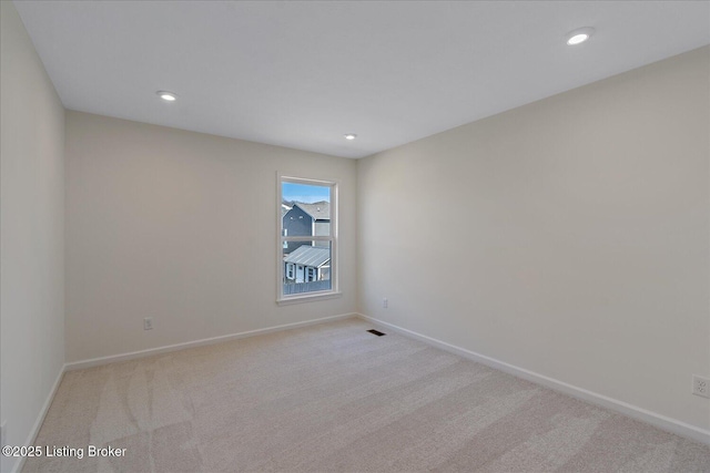 empty room with recessed lighting, light colored carpet, and baseboards