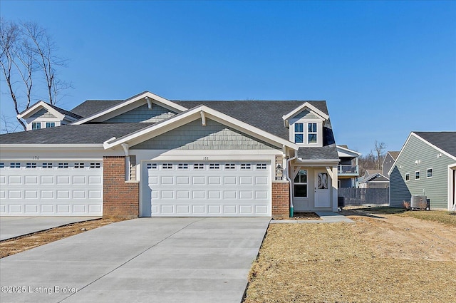 view of front of house featuring a shingled roof, brick siding, driveway, and an attached garage