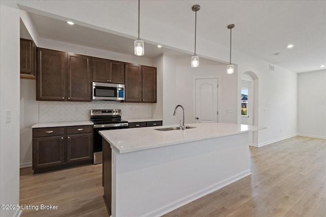 188 Harvest Moon Ct Unit 219B, Shepherdsville, KY 40165 - kitchen featuring appliances with stainless steel finishes, a sink, arched walkways, tasteful backsplash, and light wood-type flooring
