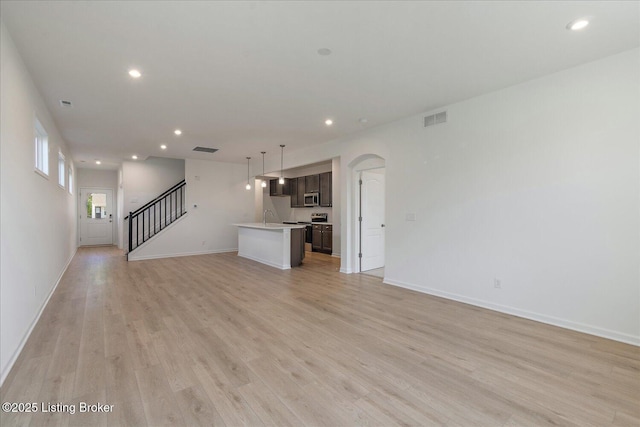 188 Harvest Moon Ct Unit 219B, Shepherdsville, KY 40165 - unfurnished living room with recessed lighting, light wood-type flooring, arched walkways, baseboards, and stairs